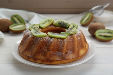 Photo of Homemade yogurt cake with kiwi and powdered sugar on white wooden table