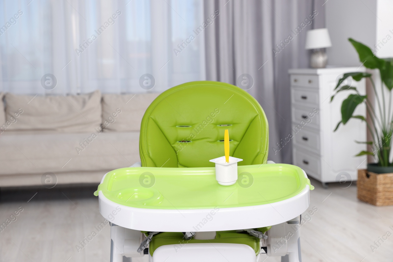 Photo of Plastic cup with tasty yogurt on high chair indoors