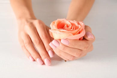 Closeup view of woman with rose at white wooden table. Spa treatment