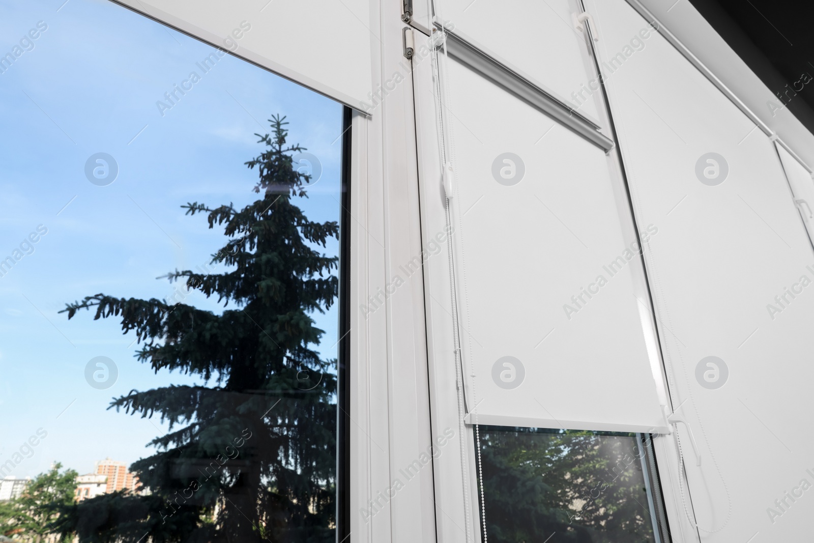 Photo of Large window with white roller blinds indoors, low angle view