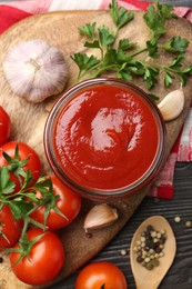 Tasty ketchup, fresh tomatoes, parsley and spices on grey wooden table, flat lay