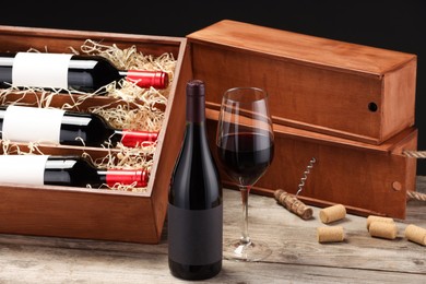 Box with wine bottles, glass, corks and corkscrew on wooden table