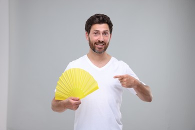 Photo of Happy man holding hand fan on light grey background