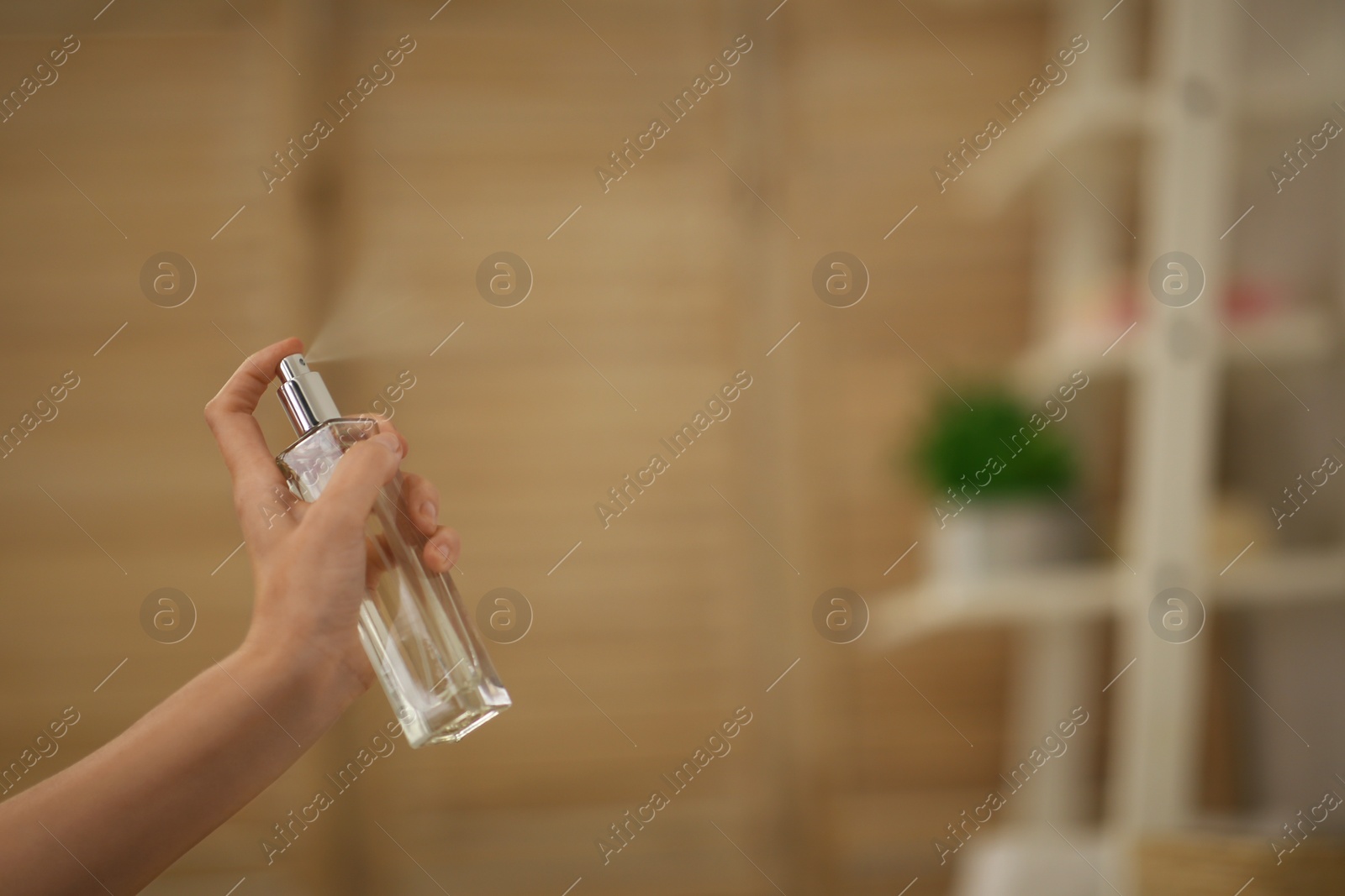 Photo of Woman spraying air freshener in bathroom, closeup. Space for text