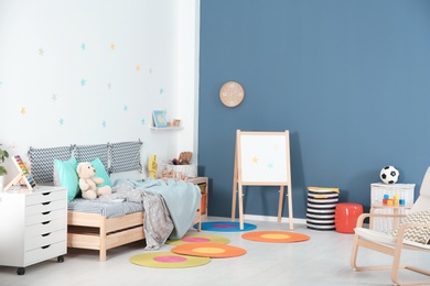 Modern child room interior with comfortable bed and armchair