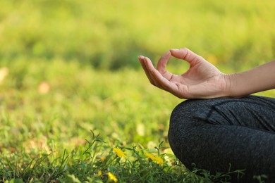 Woman meditating on green grass, closeup. Space for text