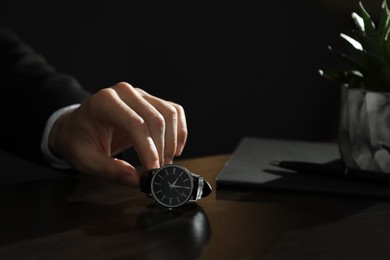 Man putting luxury wrist watch on table, closeup. Space for text