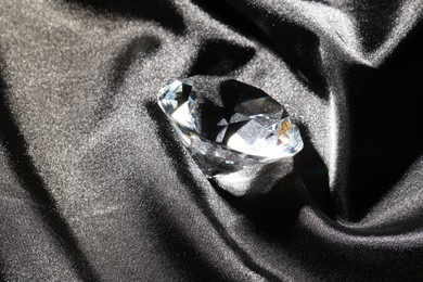 Photo of Beautiful shiny diamond on black silky fabric