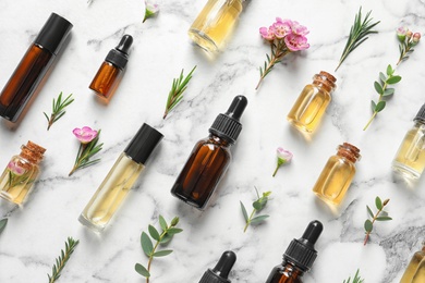 Photo of Flat lay composition with bottles of natural tea tree oil on white marble background
