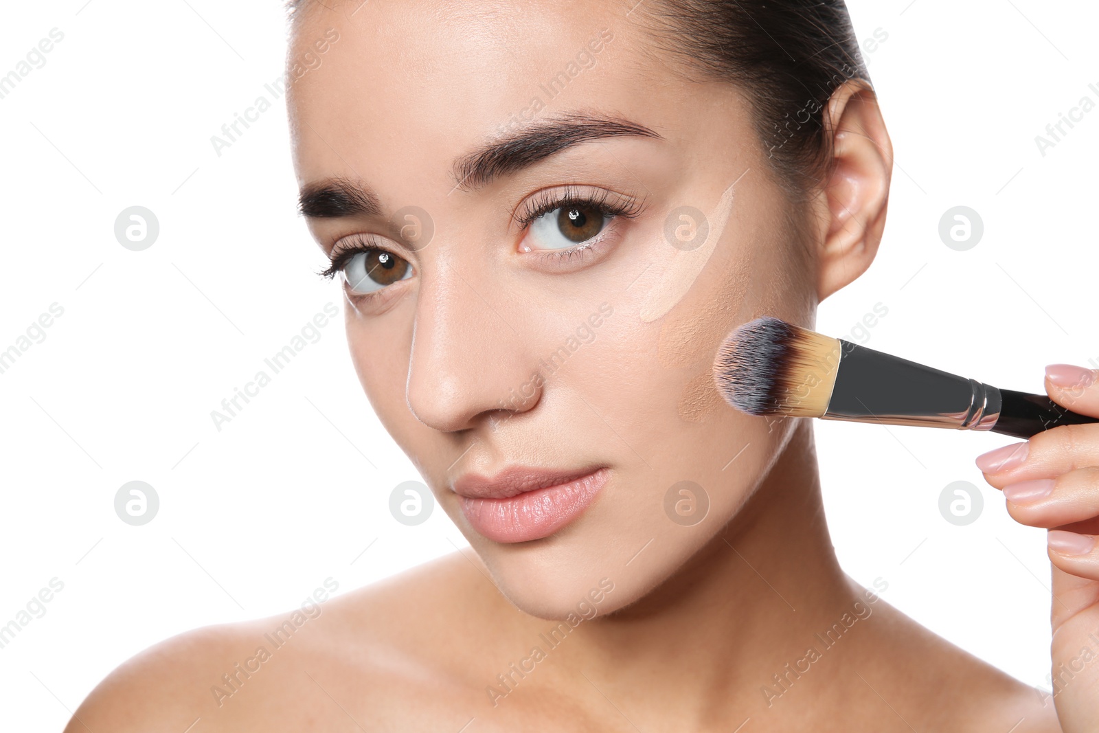 Photo of Young woman applying foundation on her face against white background