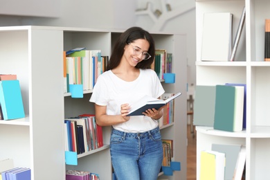 Young woman reading book in modern library