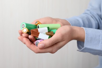 Woman holding many used electric batteries in her hands, closeup