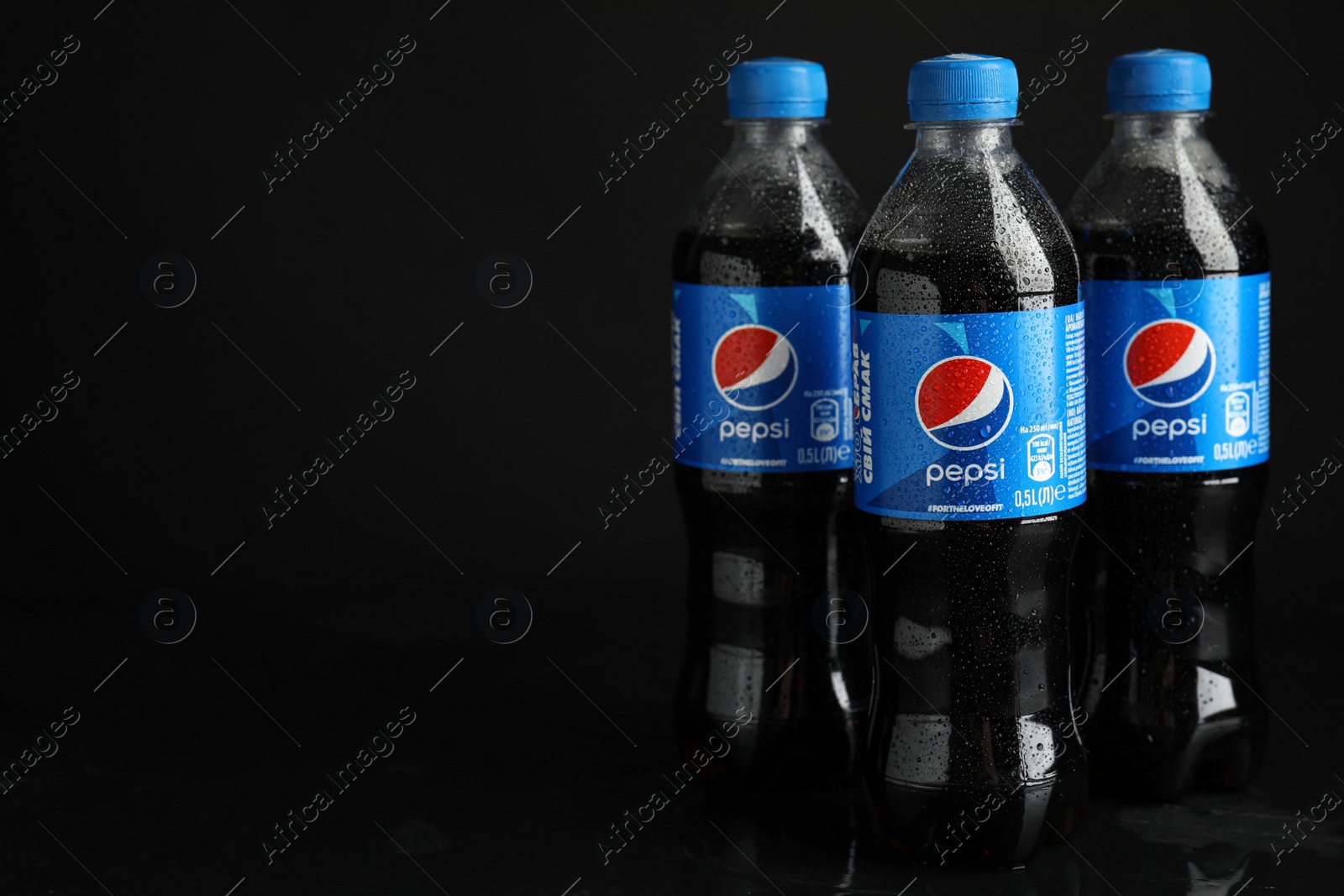 Photo of MYKOLAIV, UKRAINE - FEBRUARY 08, 2021: Plastic bottles of Pepsi with water drops on black background. Space for text