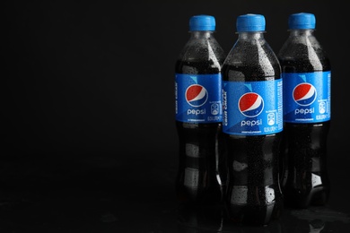 MYKOLAIV, UKRAINE - FEBRUARY 08, 2021: Plastic bottles of Pepsi with water drops on black background. Space for text