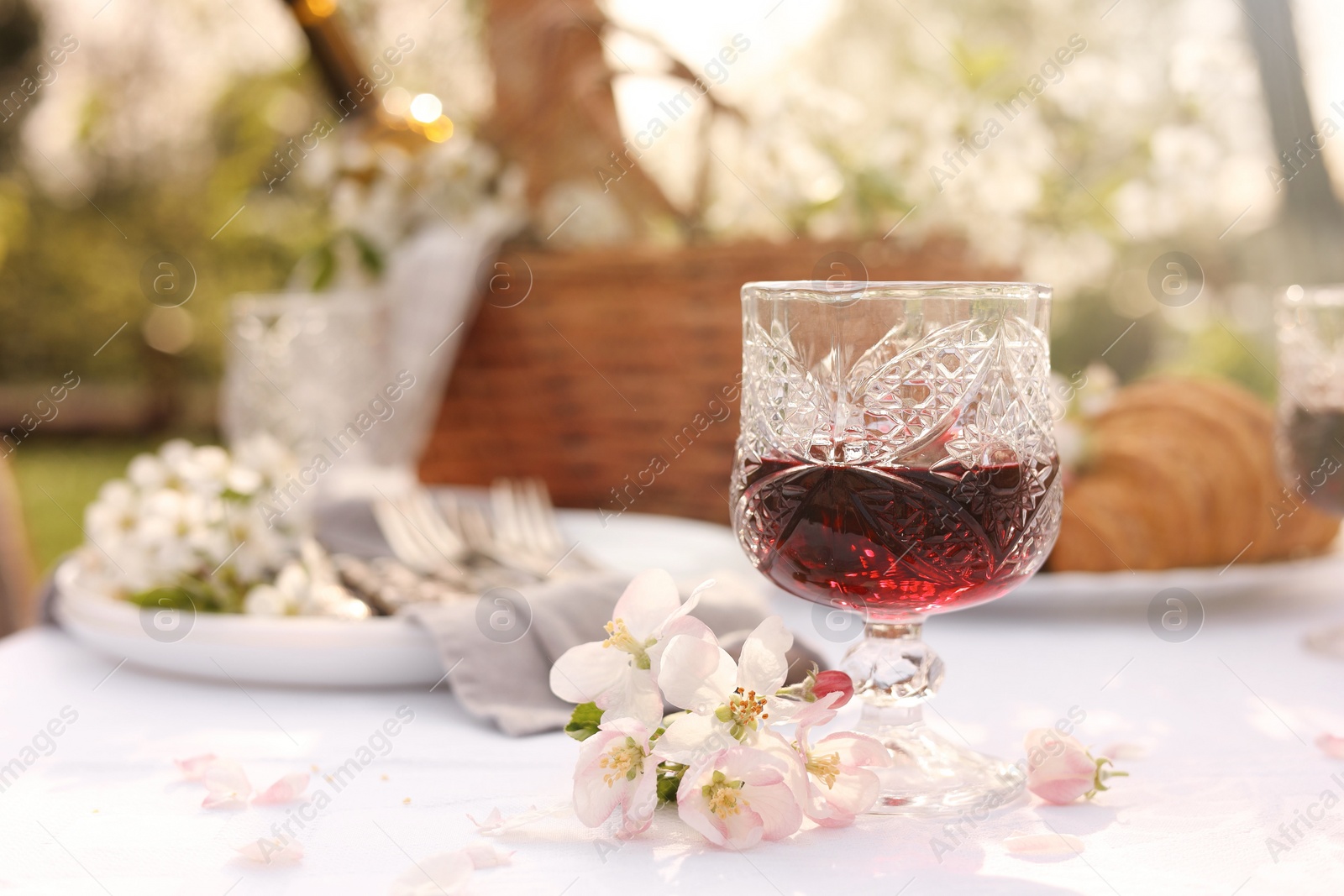 Photo of Stylish table setting with beautiful spring flowers and wine in garden