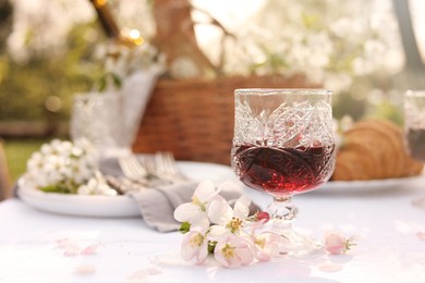 Stylish table setting with beautiful spring flowers and wine in garden