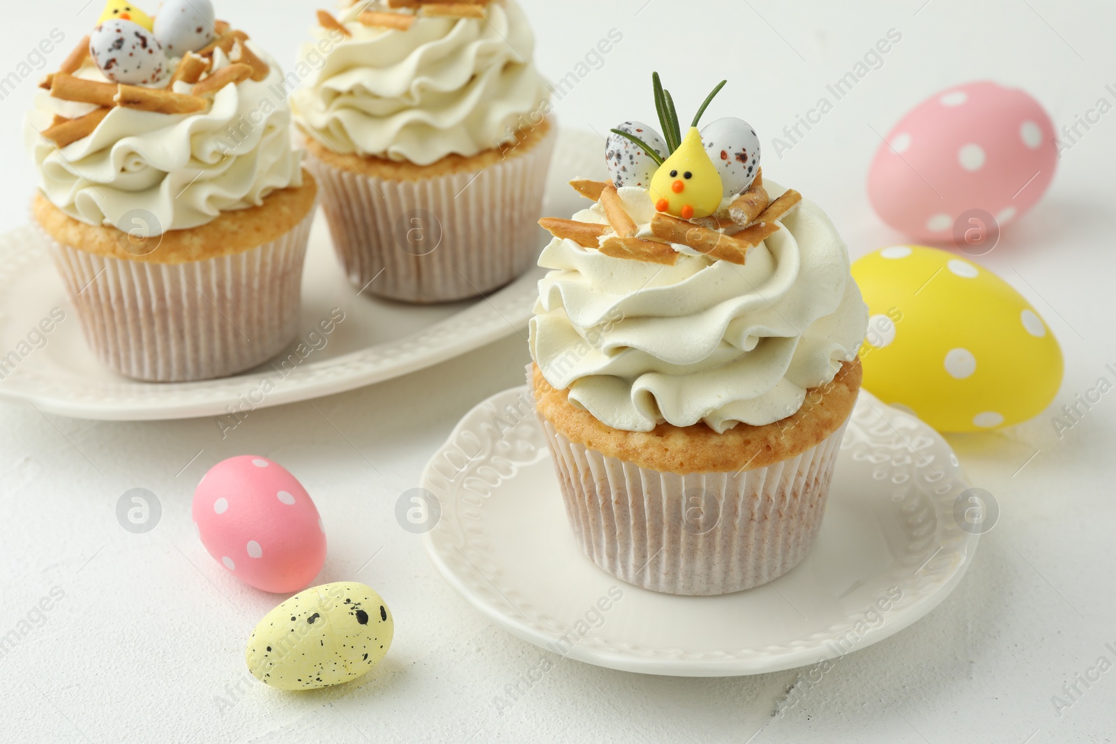 Photo of Tasty Easter cupcakes with vanilla cream on white table, closeup