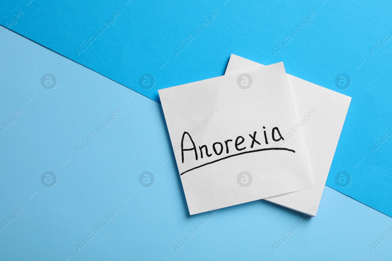 Photo of Note papers with word Anorexia on light blue background, flat lay. Space for text