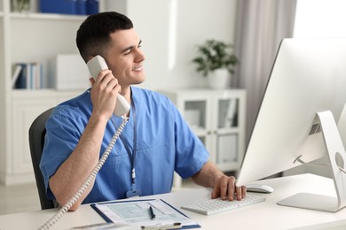 Smiling medical assistant talking by phone in office