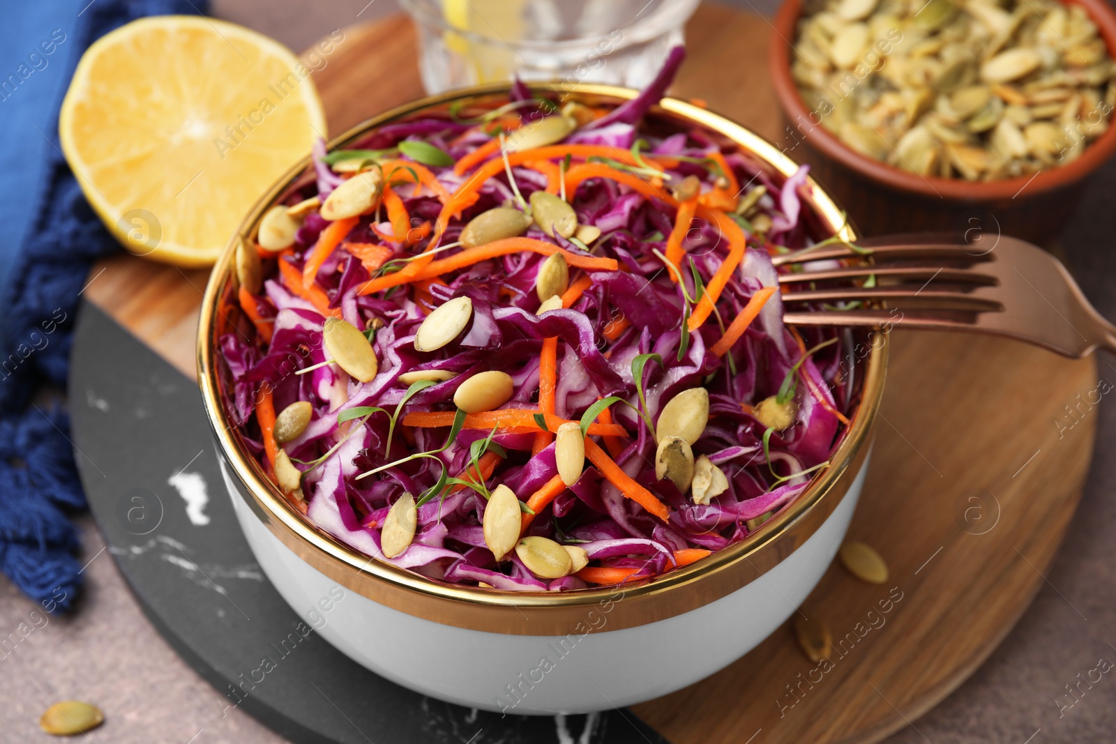 Photo of Eating tasty salad with red cabbage and pumpkin seeds on table, closeup