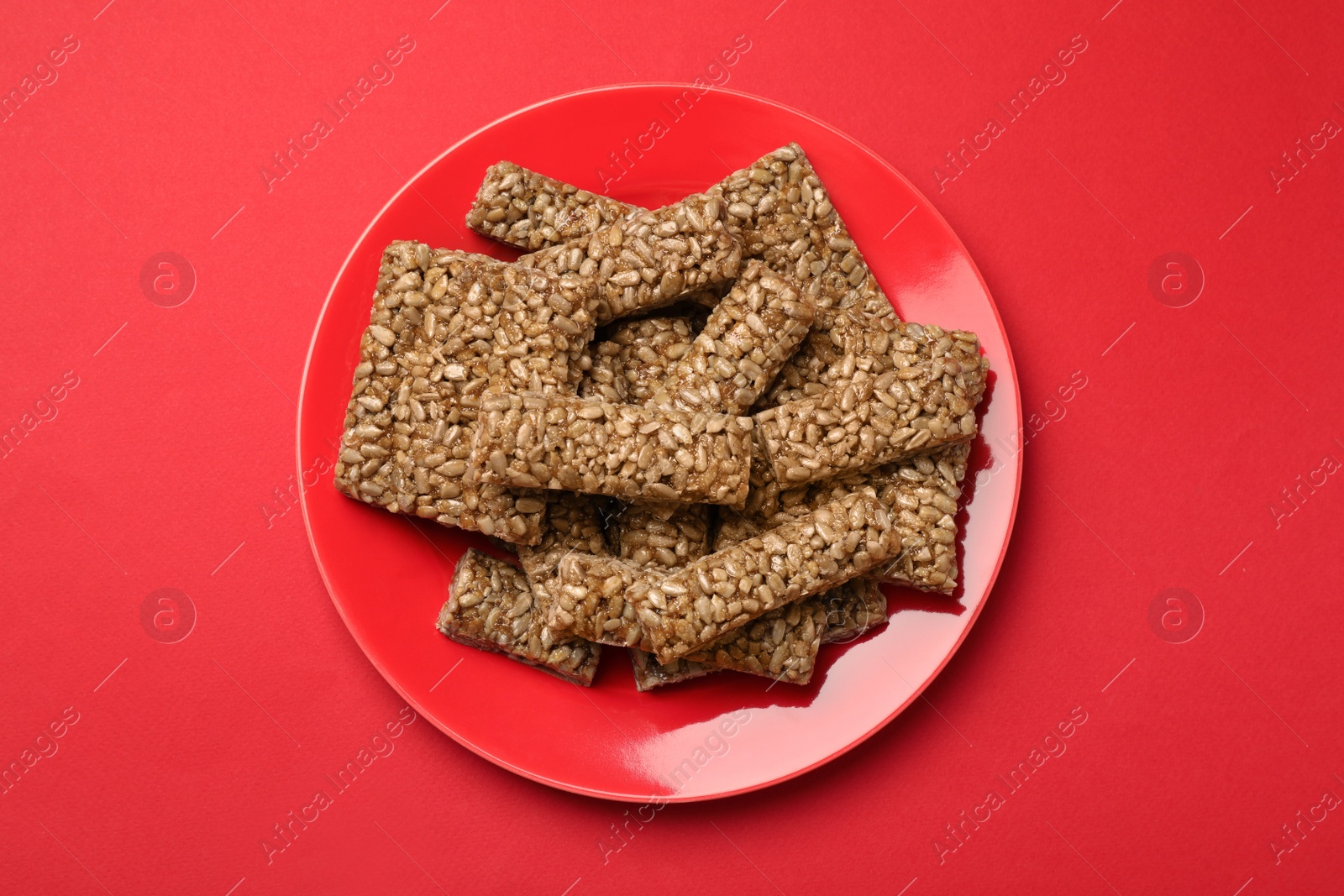 Photo of Delicious kozinaki bars on red background, top view