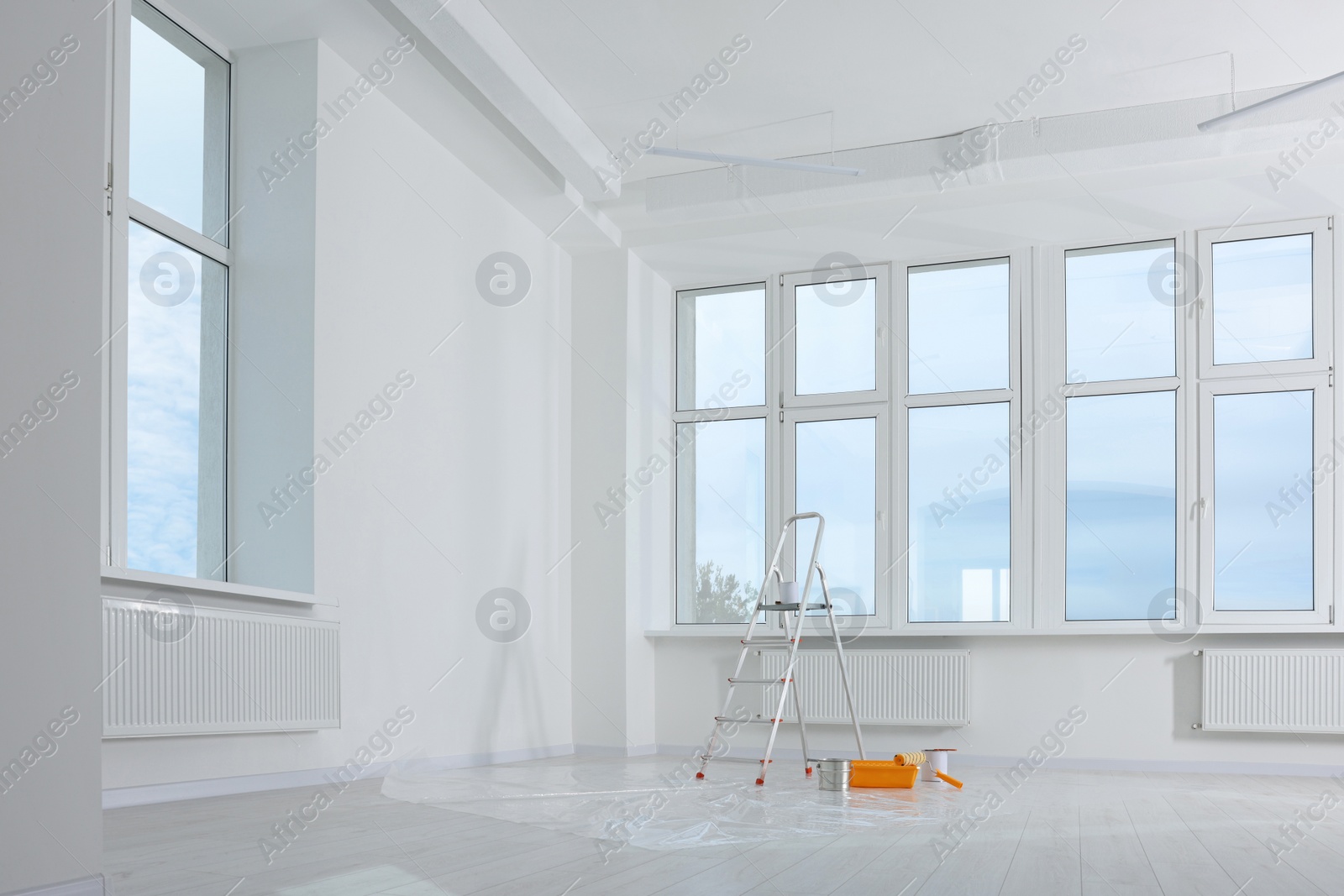 Photo of Stepladder and painting tools near window in empty room, space for text