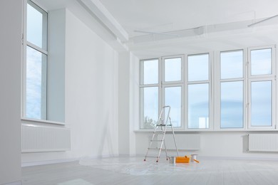 Photo of Stepladder and painting tools near window in empty room, space for text