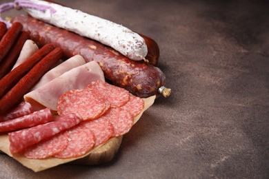 Different types of sausages on brown table, space for text