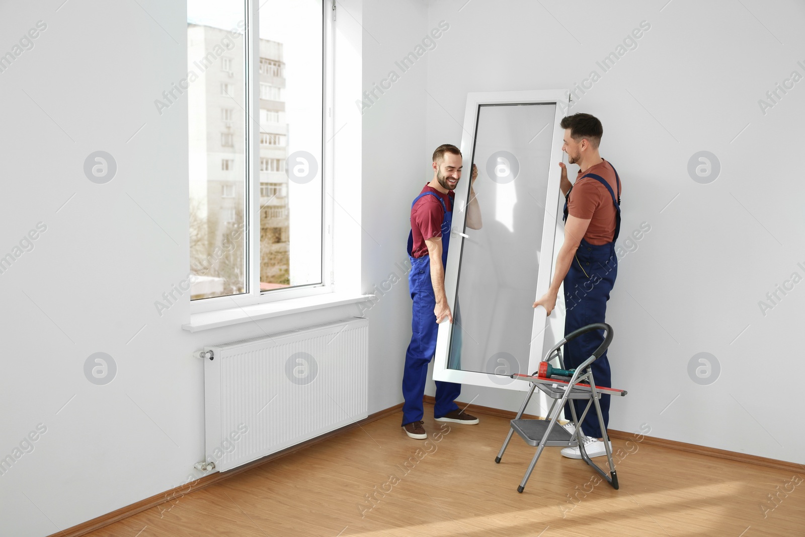 Photo of Construction workers installing plastic window in house