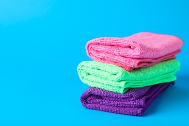 Photo of Stack of colorful microfiber cloths on light blue background. Space for text