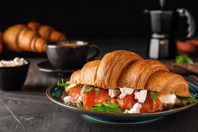 Tasty croissant sandwich with red fish on grey table