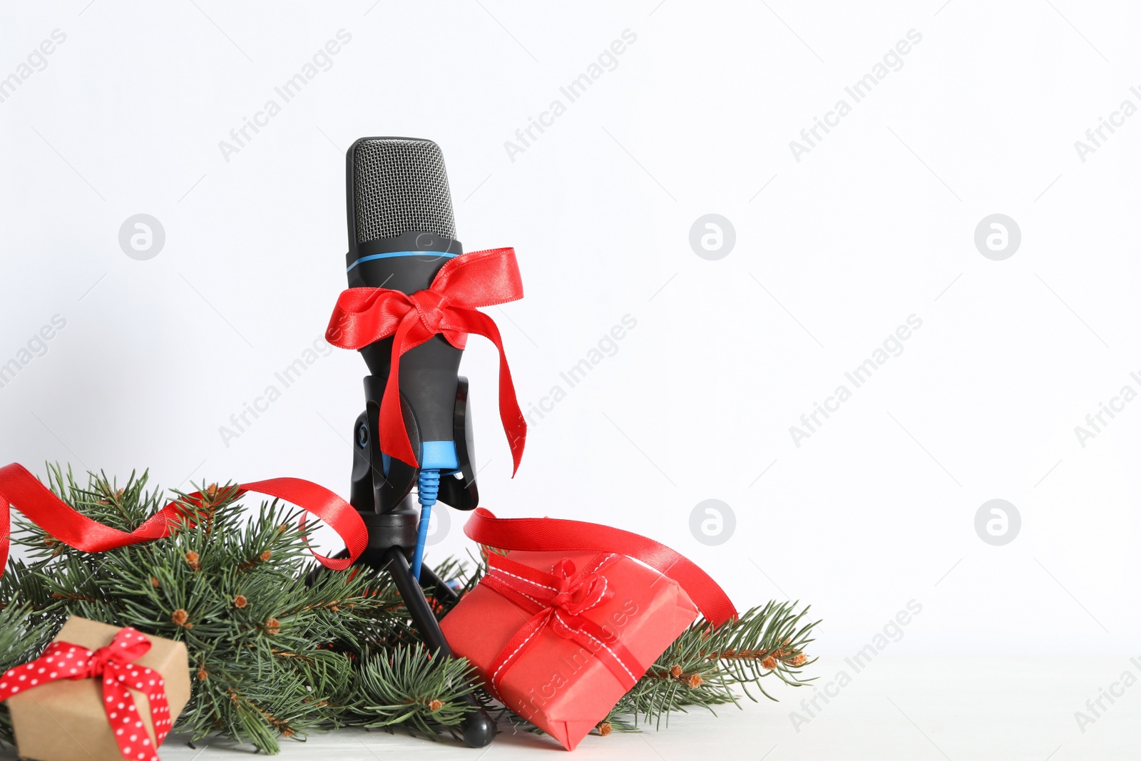 Photo of Microphone with gift boxes and festive decor on white background, space for text. Christmas music