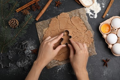 Woman making gingerbread Christmas cookies at black table, top view