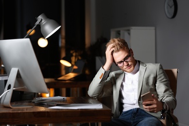 Photo of Tired young businessman working in office alone at night