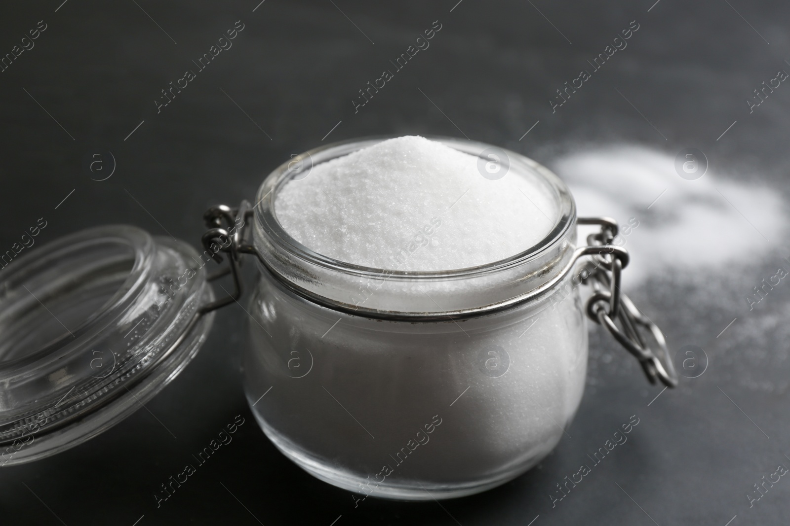 Photo of Glass jar with salt on black table, closeup