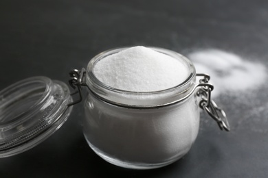 Photo of Glass jar with salt on black table, closeup