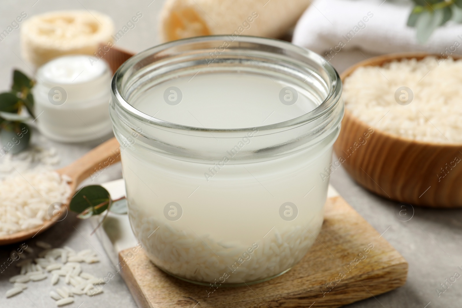 Photo of Glass jar with rice soaked in water on light grey table