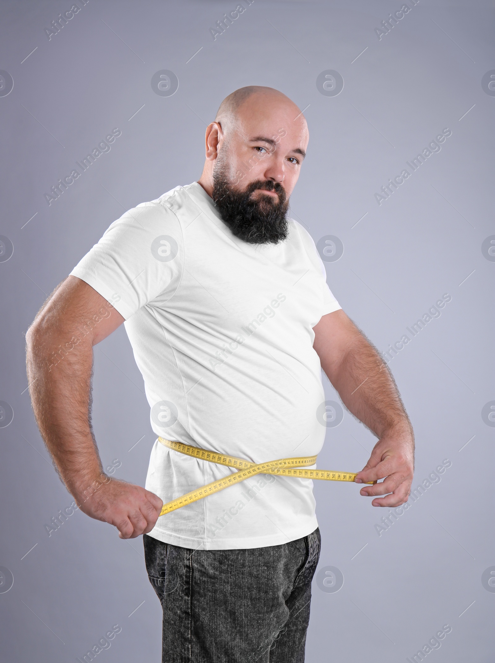 Photo of Fat man with measuring tape on grey background. Weight loss