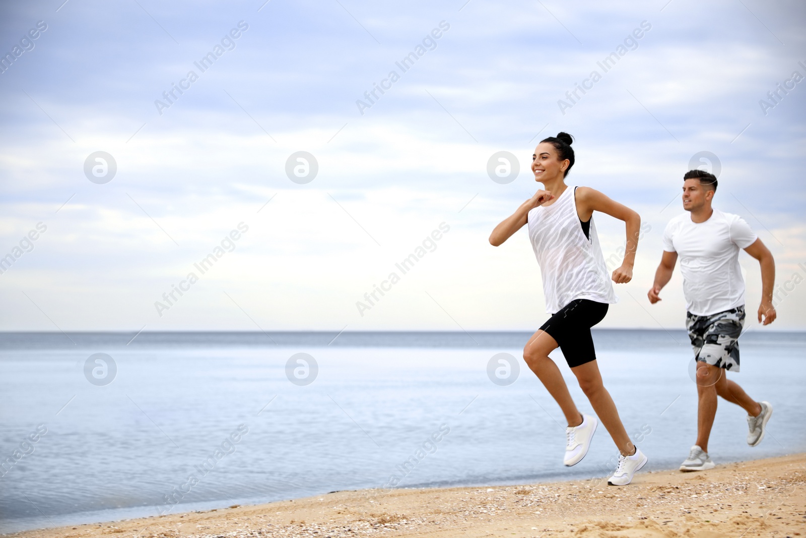 Photo of Couple running together on beach, space for text. Body training