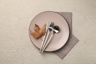 Stylish table setting with cutlery and dry leaf on light surface, top view