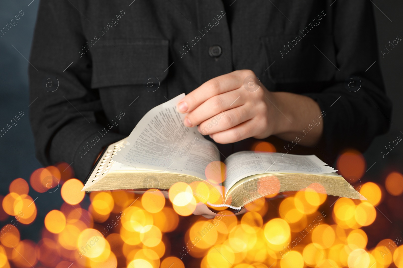 Image of Woman reading Bible, closeup view. Bokeh effect