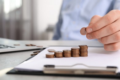 Man stacking coins at table indoors, closeup