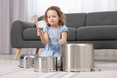 Little girl pretending to play drums on pots at home