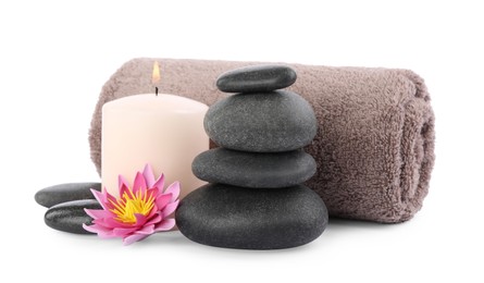 Photo of Stack of spa stones, towel, flower and candle isolated on white