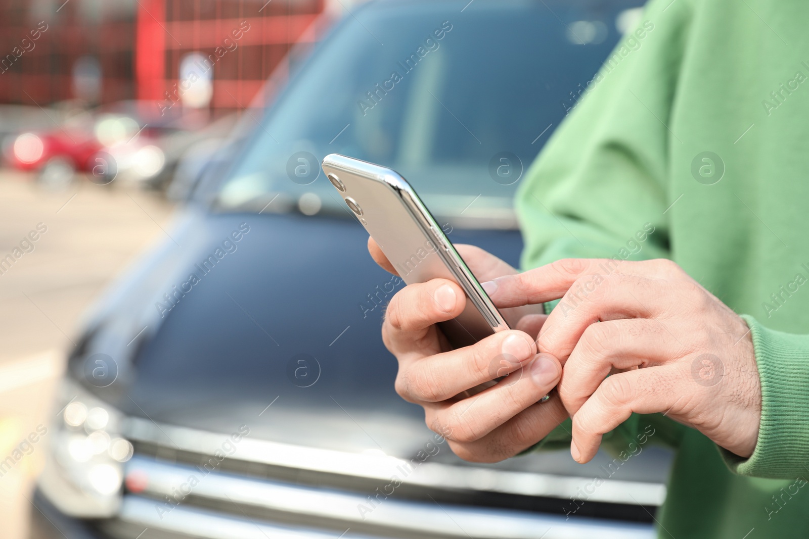 Photo of Man ordering taxi with smartphone on city street, closeup