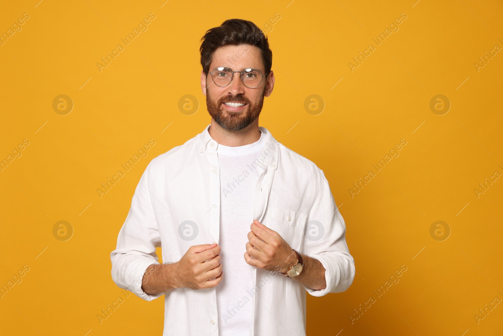 Photo of Portrait of smiling bearded man with glasses on orange background