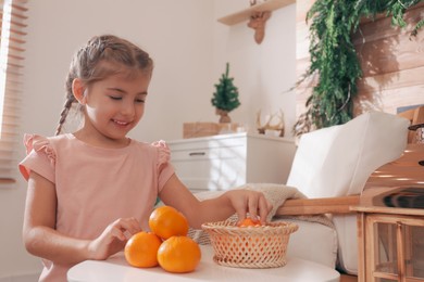 Photo of Cute little child with fresh tangerines at home