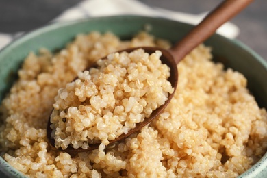 Cooked quinoa in bowl and wooden spoon, closeup