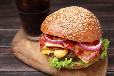 Delicious burger with bacon, patty and vegetables on wooden table, closeup