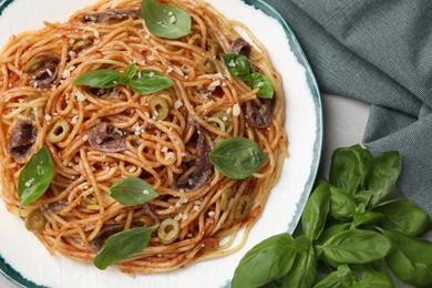 Photo of Delicious pasta with anchovies, tomato sauce and basil on table, top view